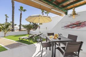 a patio with a table and chairs and an umbrella at Jardin del sol 17 in Playa Blanca