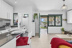 uma cozinha e sala de jantar com armários brancos e cadeiras vermelhas em Jardin del sol 17 em Playa Blanca