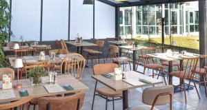 un restaurante con mesas y sillas de madera y ventanas en Best Western Hotel Braunschweig, en Brunswick