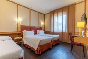 pokój hotelowy z dwoma łóżkami i biurkiem w obiekcie Best Western Hotel President - Colosseo w Rzymie