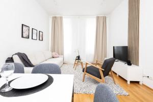 ein weißes Wohnzimmer mit einem weißen Sofa und Stühlen in der Unterkunft OrestaLiving - 2BR On the Danube Canal in Wien