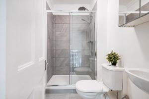 a white bathroom with a toilet and a shower at Hyde Park Modern Apartments in London