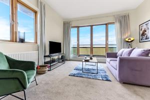 ein Wohnzimmer mit einem lila Sofa und einem TV in der Unterkunft City Penthouse with Scenic View Balcony in Milton Keynes
