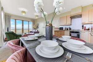 a dining room table with white dishes and a vase with flowers at City Penthouse with Scenic View Balcony in Milton Keynes
