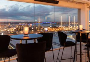 a room with tables and chairs and a view of a city at Rydges Auckland in Auckland