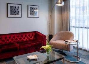 a living room with a red couch and a chair at Rydges Auckland in Auckland