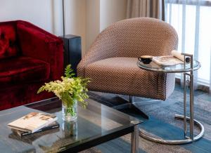 a living room with a chair and a glass table at Rydges Auckland in Auckland