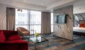 a living room with a red couch and a bed at Rydges Auckland in Auckland