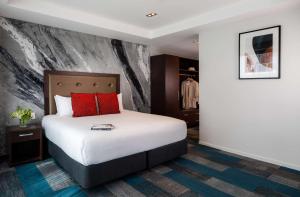 a hotel room with a bed with red pillows at Rydges Auckland in Auckland