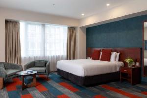 a hotel room with a bed and two chairs at Rydges Auckland in Auckland