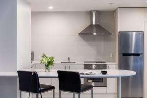 a kitchen with a table and chairs and a refrigerator at Rydges Auckland in Auckland