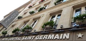 a building with potted plants and a street sign at Hôtel Central Saint Germain in Paris