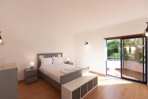 une chambre blanche avec un lit et une grande fenêtre dans l'établissement FLH Caparica Town House with Pool, à Costa da Caparica