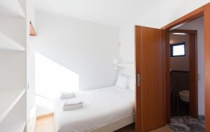 - une petite chambre avec un lit blanc et une porte en bois dans l'établissement FLH Caparica Town House with Pool, à Costa da Caparica