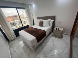een slaapkamer met een bed en een groot raam bij Residencial Santo Amaro in Tarrafal