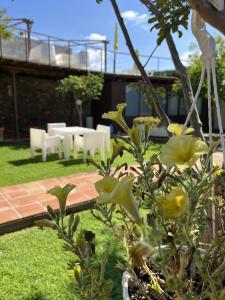 un jardín con un patio con sillas blancas y flores en El Secanet en Algimia de Alfara