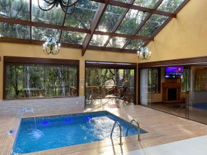 an indoor pool in a house with a glass ceiling at Chalés Recanto das Montanhas in Monte Verde