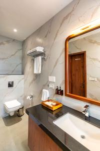ein Badezimmer mit einem Waschbecken, einem WC und einem Spiegel in der Unterkunft The Grand Fateh in Udaipur