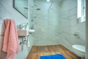 uma casa de banho com um chuveiro, um lavatório e um WC. em Modern 1BR Stylish Maisonette with Yard - Bugibba Promenade em St. Paul's Bay