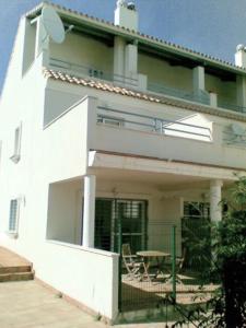 una casa blanca con una mesa delante en NPG429 - Holiday Beach House on the Golf Course, en Huelva