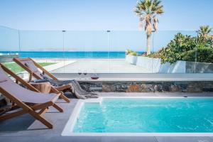 a swimming pool with two chairs and a table at Niriides Palace in Gournes