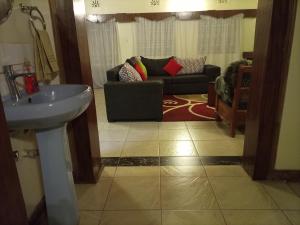 a bathroom with a sink and a living room at The Tipping Hat, Eldoville in Eldoret