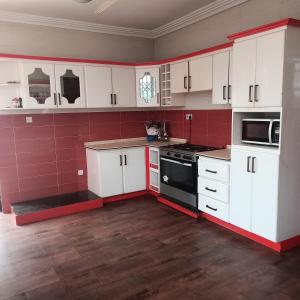 a kitchen with white cabinets and a black stove at jetfastventure in Accra