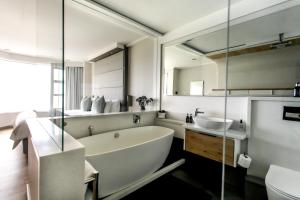 a bathroom with a large tub and a sink at Bayview 203 in Hermanus