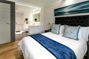 een slaapkamer met een groot wit bed met blauwe kussens bij Bayview 203 in Hermanus