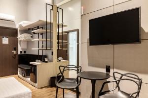 Tri Hotel Premium Itapema في ايتابيما: غرفة معيشة مع طاولة وكراسي وتلفزيون