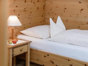 Cama con almohadas blancas y mesa con lámpara en Appartements Spullersee, en Lech am Arlberg