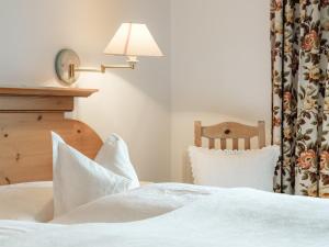 a bedroom with a bed with white sheets and a lamp at Appartements Spullersee in Lech am Arlberg