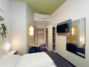 a hotel room with a bed and a desk and a tv at B&B HOTEL Berlin-Potsdamer Platz in Berlin