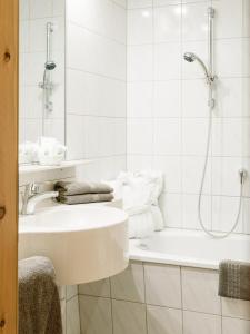 a white bathroom with a sink and a shower at Appartements Spullersee in Lech am Arlberg