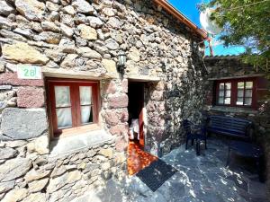 una casa de piedra con un banco junto a un edificio en Casa rural con 2 dormitorios con barbacoa y preciosa vista, en Mocanal