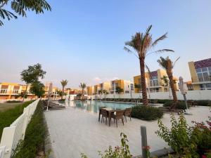 een patio met een tafel en stoelen naast een zwembad bij Modern 3BR Villa, DAMAC Hills 2 in Dubai