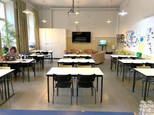 a classroom with tables and chairs and a woman sitting at a table at Hostel Suomenlinna in Helsinki