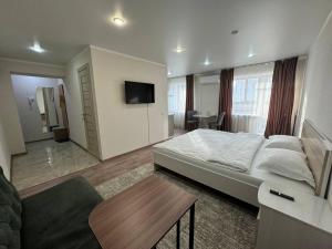 1 dormitorio con 1 cama grande y TV en Светлые и уютные апартаменты с выходом в центральный парк, en Kostanái