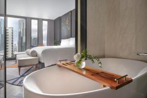 een badkamer met een bad en een slaapkamer met een bed bij InterContinental Bangkok Sukhumvit, an IHG Hotel in Bangkok
