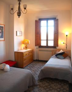een slaapkamer met 2 bedden, een raam en een dressoir bij Appartamento via Grandi - Free Gated Parking - 5 minutes from Center in Lucca