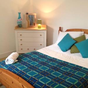 een slaapkamer met een bed met blauwe kussens en een dressoir bij Apple Tree Apartment in Pembroke