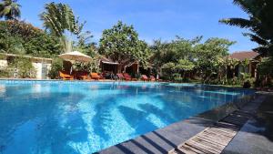 a large swimming pool with chairs and an umbrella at Paradiso Phu Quoc Resort in Phu Quoc