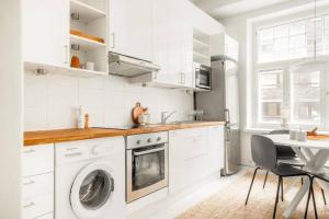a white kitchen with a washing machine and a table at Downtown Light-Filled Retreat in Helsinki