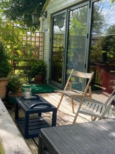 uma cadeira de baloiço e uma mesa num alpendre em ‘The Den’ Self contained one bedroom annexe. em Stockbridge