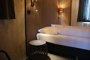 a bedroom with a bed with a stool next to it at Wellnesslodge Grutto in Dalerveen