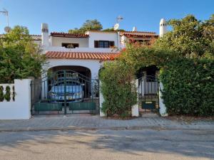 Biały dom z bramą i krzakami w obiekcie Casa das Flores w Albufeirze