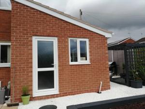 a red brick house with two windows on it at Self contained annexe in Kidderminster