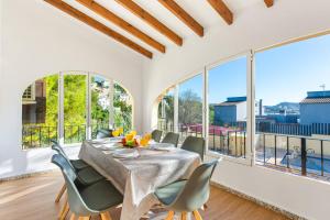 a dining room with a table and chairs and large windows at Villa Enzo - PlusHolidays in Moraira