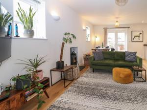 a living room with a green couch and a rug at 1 Matrons Cottages in Littlehampton