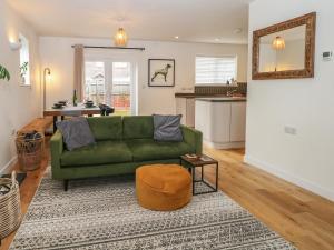 a living room with a green couch and a kitchen at 1 Matrons Cottages in Littlehampton